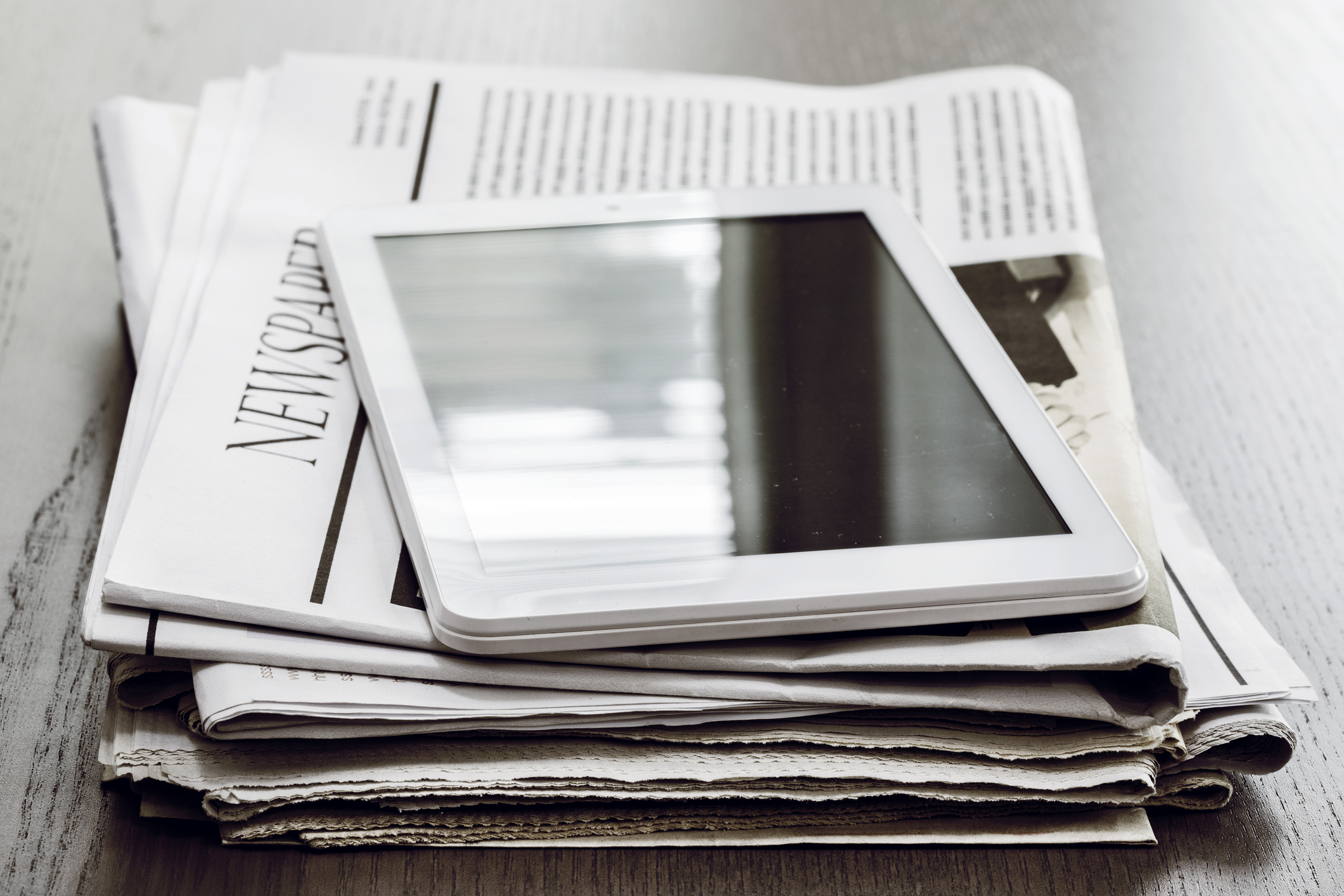 A tablet sitting on top of some newspapers.