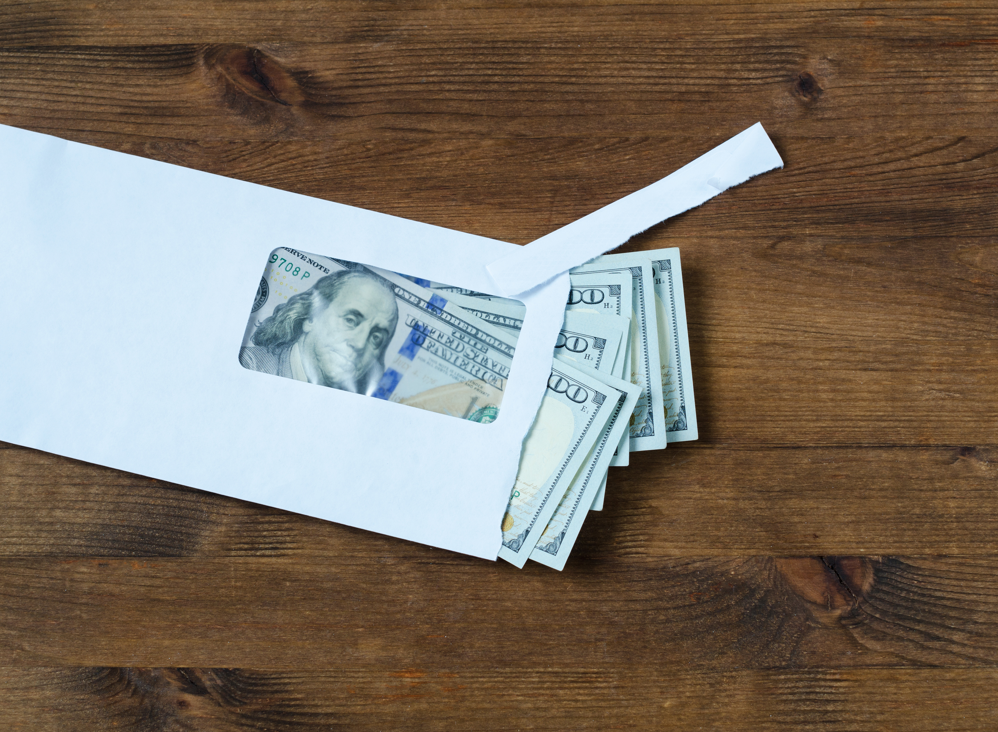 Stack of hundred dollar bills in an envelope.