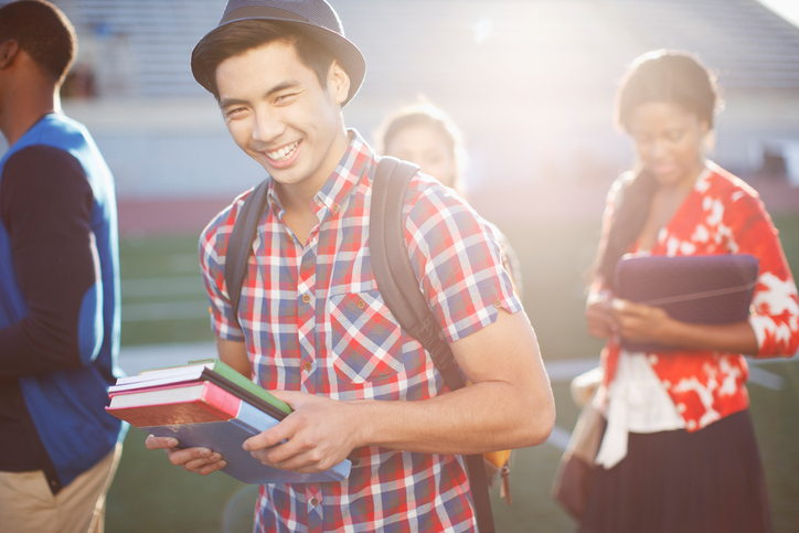 Smiling male student holding textbooks.
