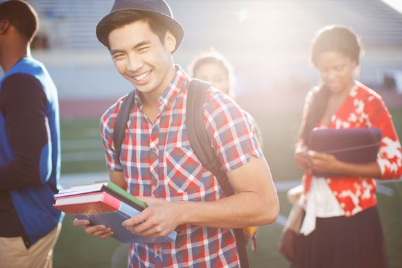 Smiling male student holding textbooks.
