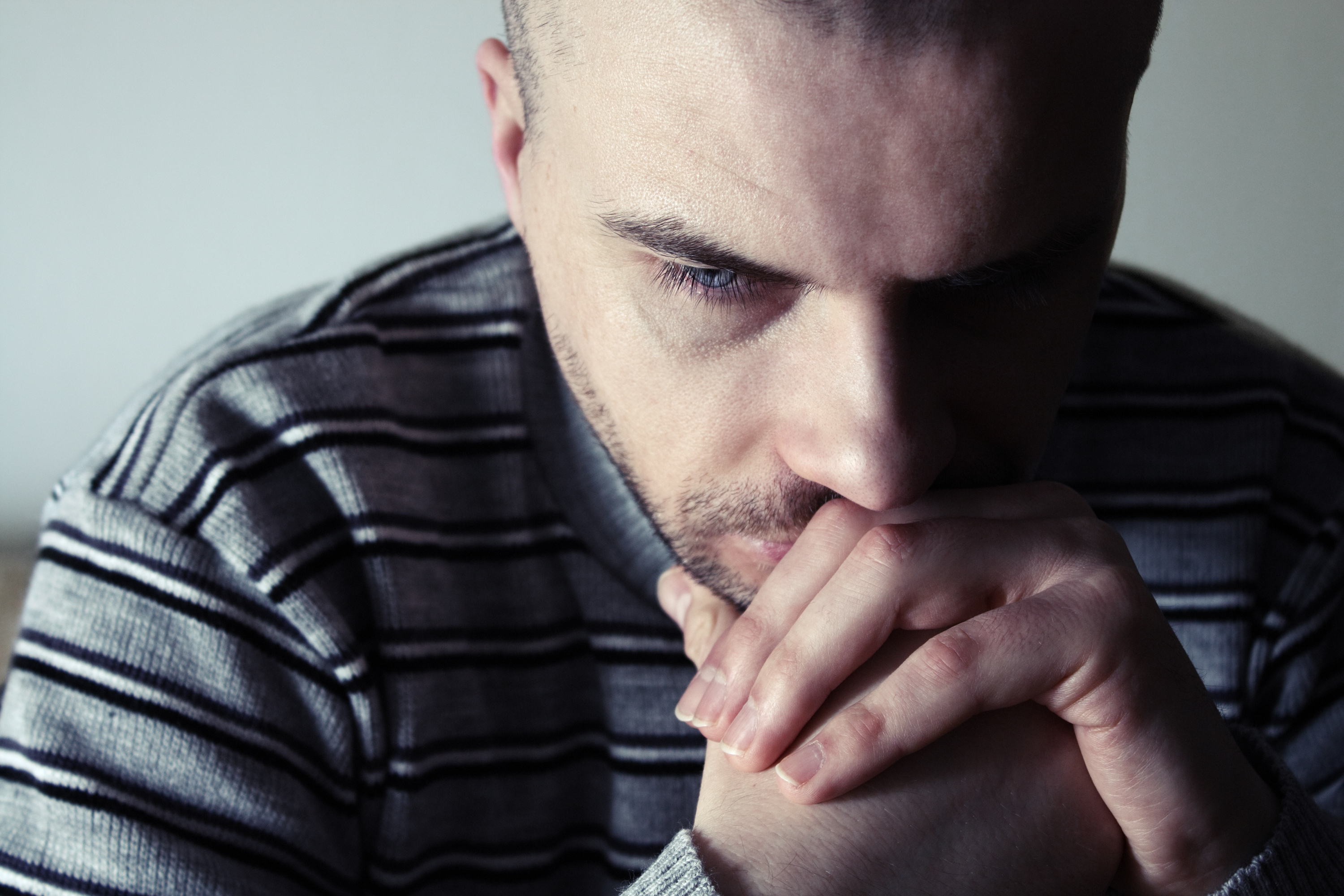 Serious-looking man with his face resting on his hands.