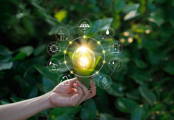 A hand holding a flower that is lighting up and emitting icons representing various renewable energy sources.
