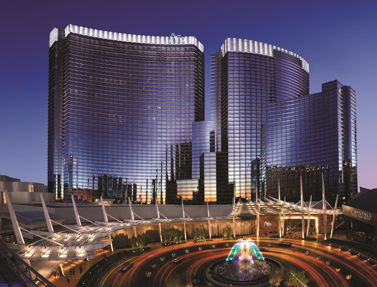 Aria casino resort at dusk with lighted fountain in front.