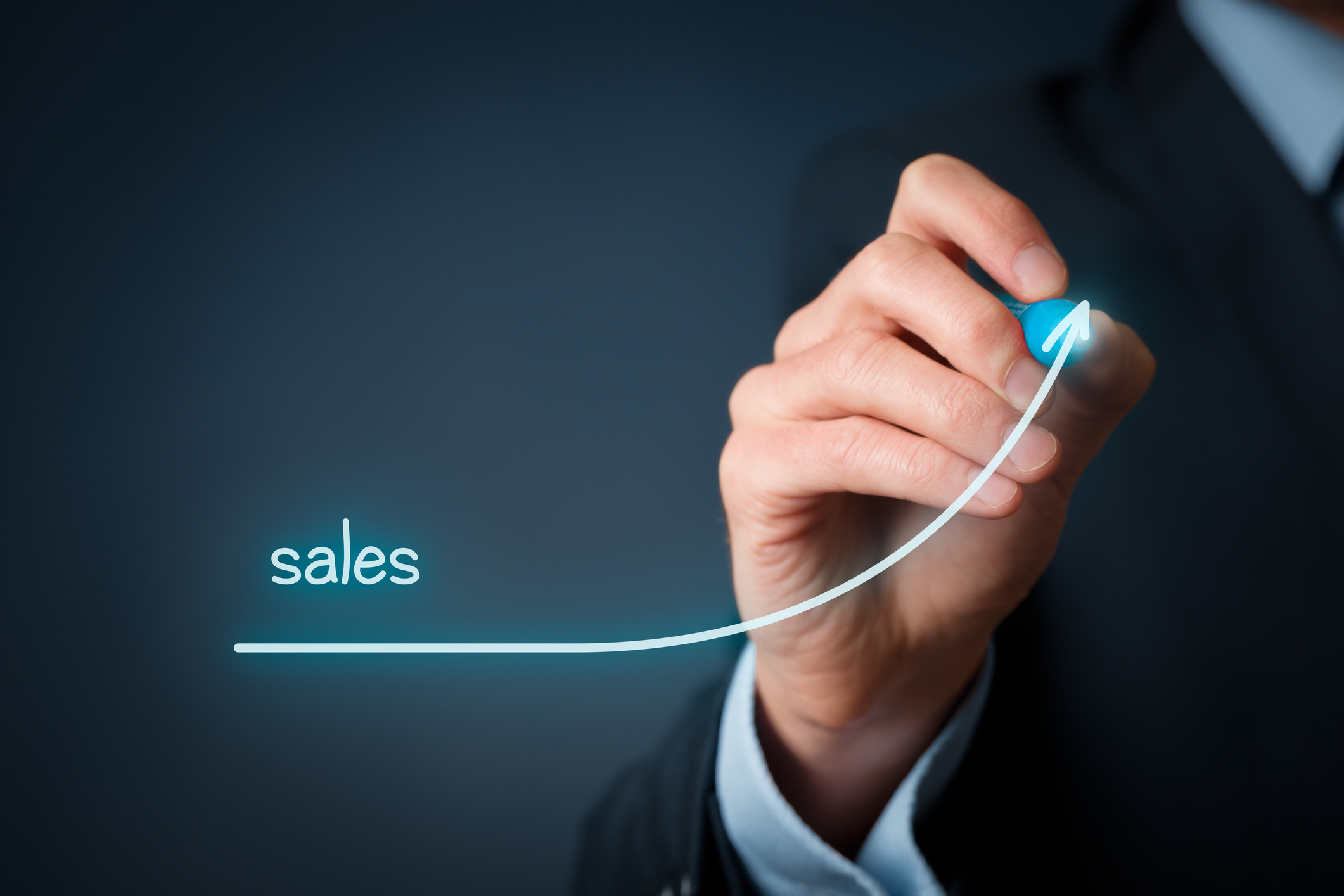 A person drawing an upwardly sloping curve labeled sales