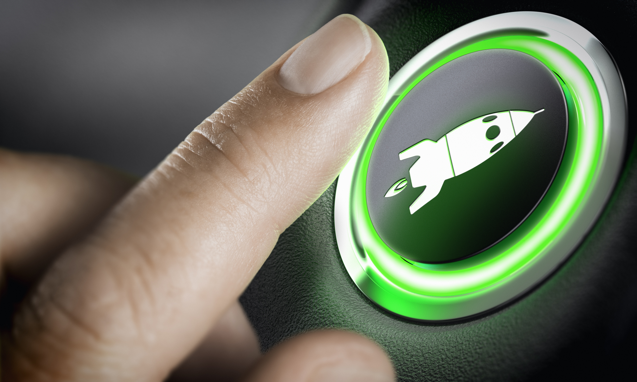 Finger reaching to press a green lighted button depicting a rocketship.