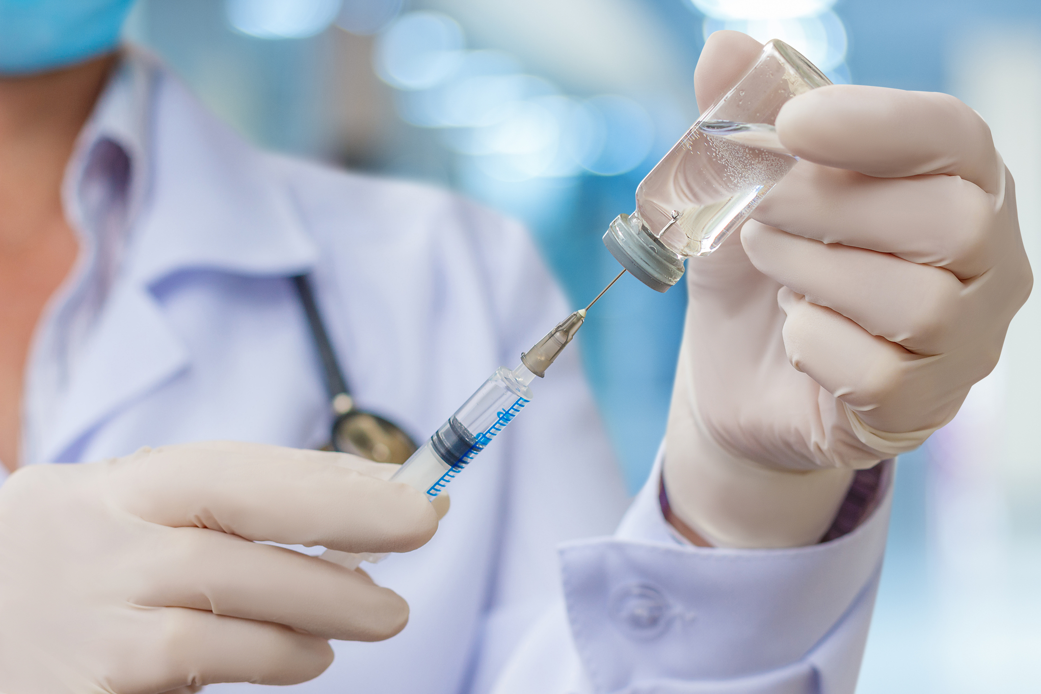 Doctor using syringe to draw medication from a vial