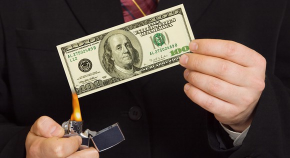 Hands lighting a $100 bill on fire