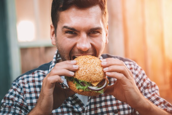 A man takes a bite out of a burger.