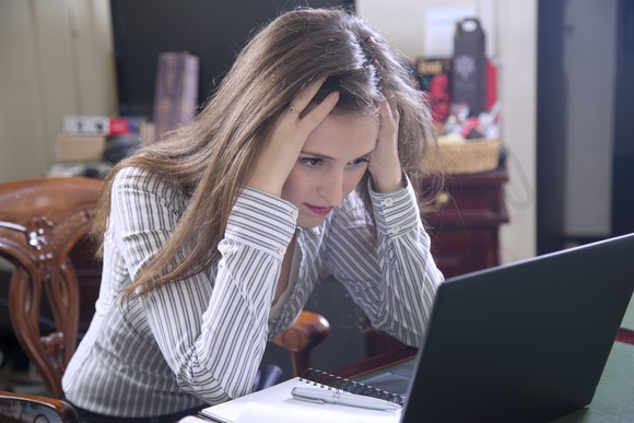 A frustrated woman reading something on her laptop.