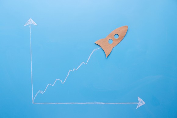 A paper cutout of a rocket at the top of an ascending chart line.