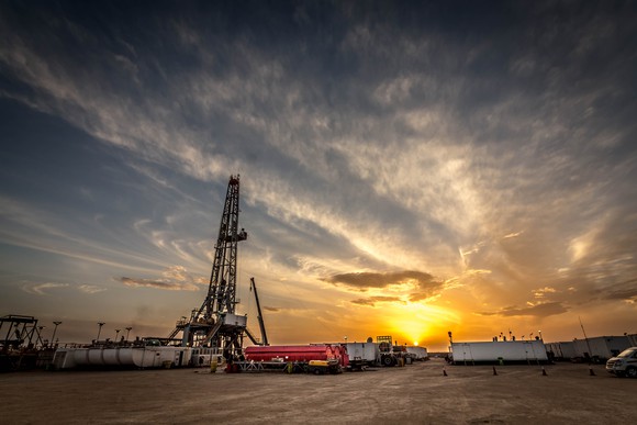 A drilling rig with the sun setting in the background.