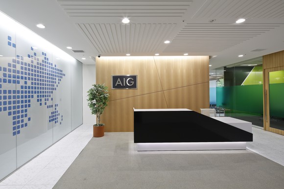 Lobby of an office with stylized world map, modern furnishings, and AIG logo on the wall.