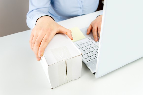 Man on a laptop with a plain white box next to it.