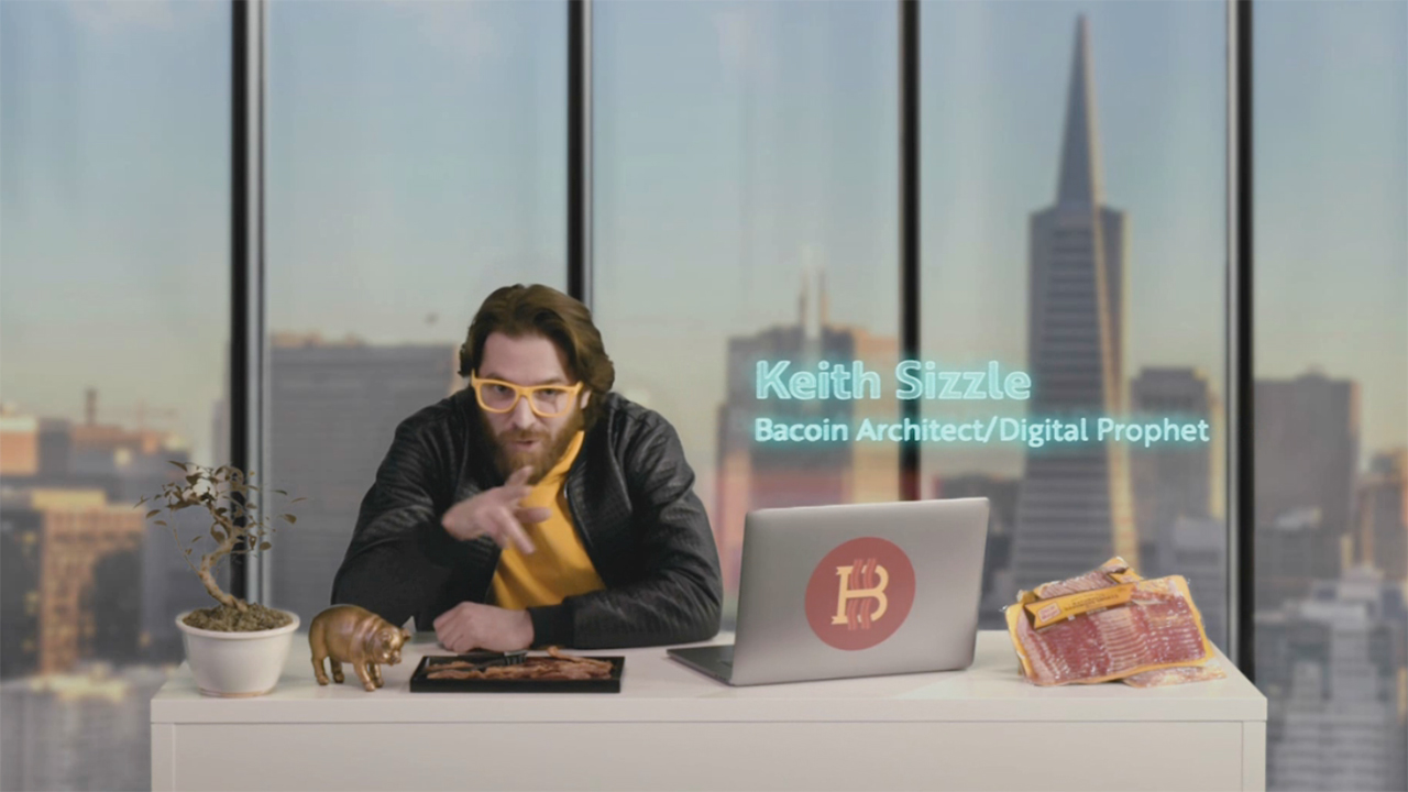 a man sits at a desk with Oscar Meyer meats and a laptop and funny glasses.