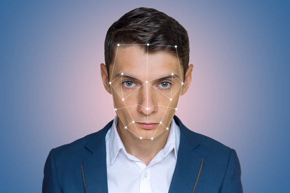 A young man looks into the camera and augmented reality dots on his face.