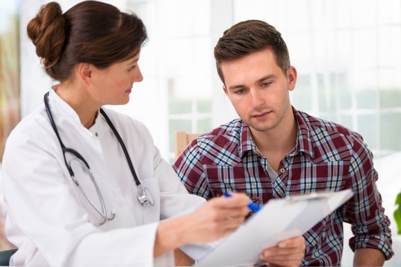 Doctor showing a male patient something on a clipboard