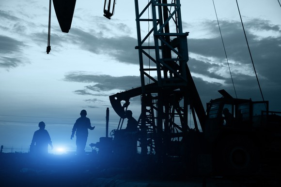 Oil workers near some oil pumps.