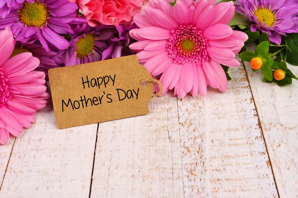 A happy Mother's Day sign sits in front of some flowers.