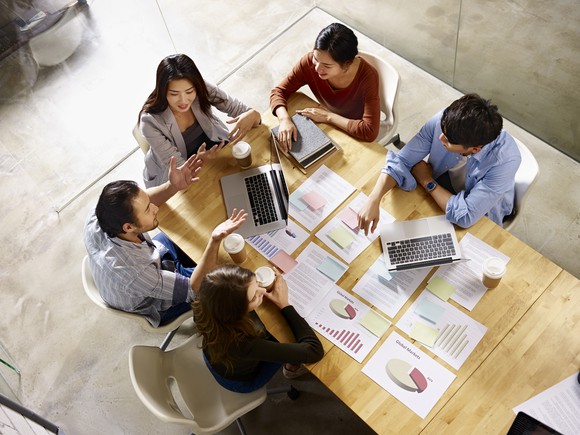 A group of people sit around a table in a meeting.