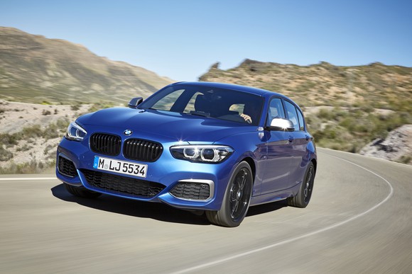 A blue BMW 1 Series, a small premium sedan, on a mountain road