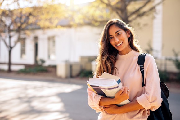 Young woman with backpack holding books