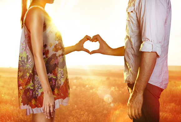 A woman and a man touching their hands together in the shape of a heart