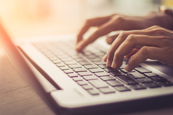 Closeup of hands typing on a laptop computer.