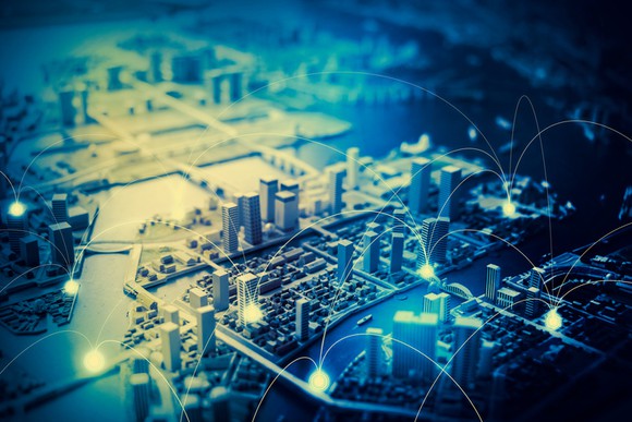 A graphic of a city from overhead with blue points being connected through the air with giant arcs.