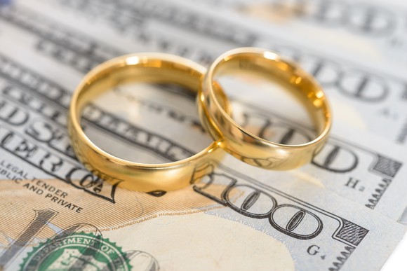 two gold rings sitting on some hundred dollar bills