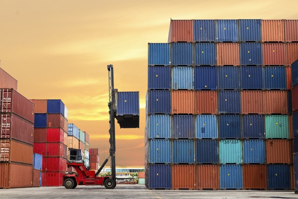 Shipping containers at port being organized by a forklift.