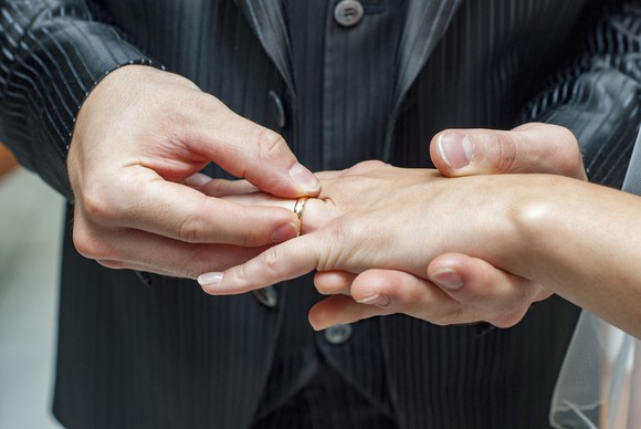 A man puts a wedding ring on a woman's finger.