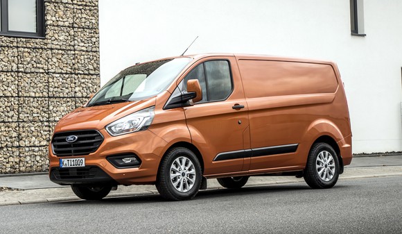 An orange 2018 Ford Transit Custom, a commercial van about the length of a midsize sedan, on a European street