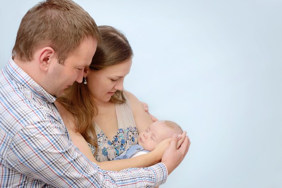 A mother and father cradle their newborn baby.