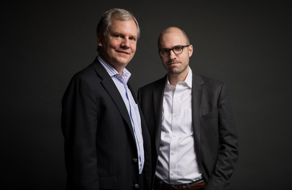 Arthur Sulzberger, Jr. and A. G. Sulzberger pose in suits for a professional photo with a black background.