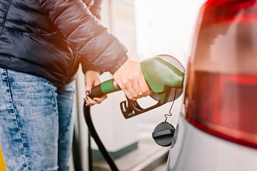 A woman pumping gas in her car.