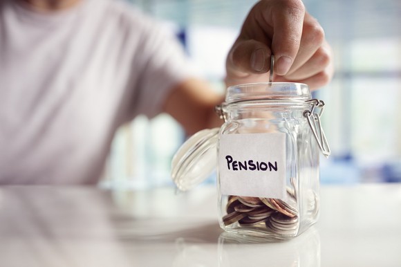 Hand placing change into a jar labeled "pensions"