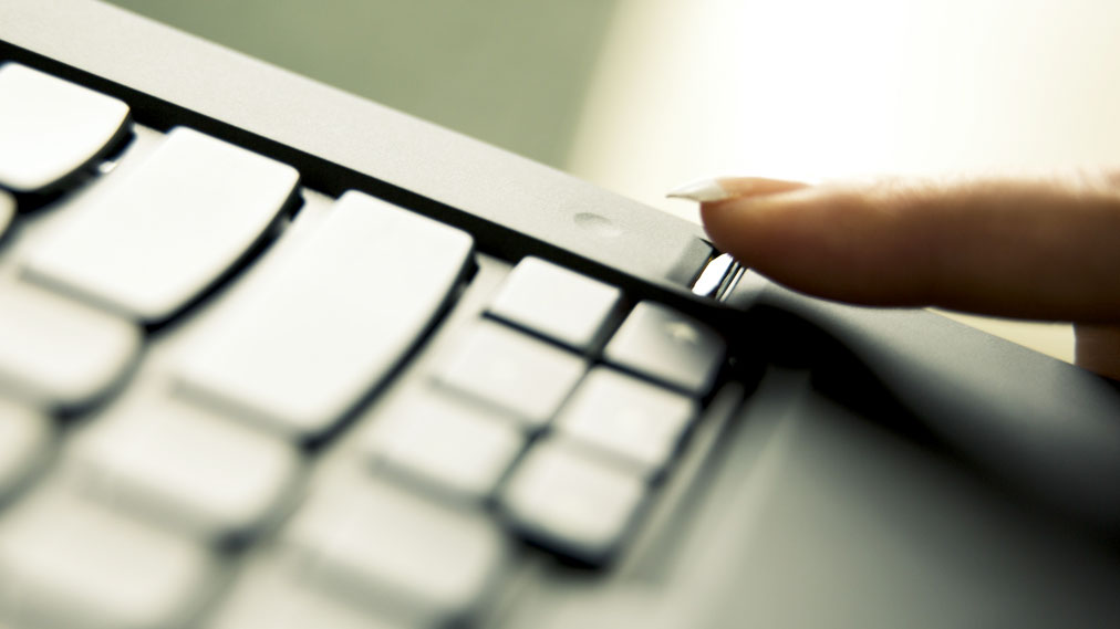 A woman's finger using a fingerprint sensor on a laptop.