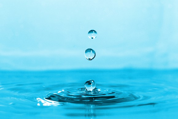 Three droplets of water falling into a body of water and creating ripples.