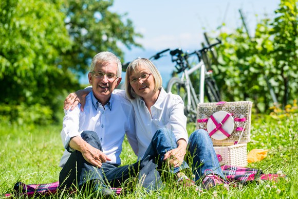 Senior couple sitting on the grass in front of a picnic basket