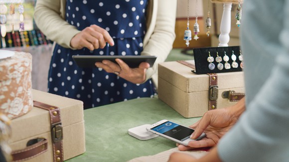 A person paying using a Square contactless reader.
