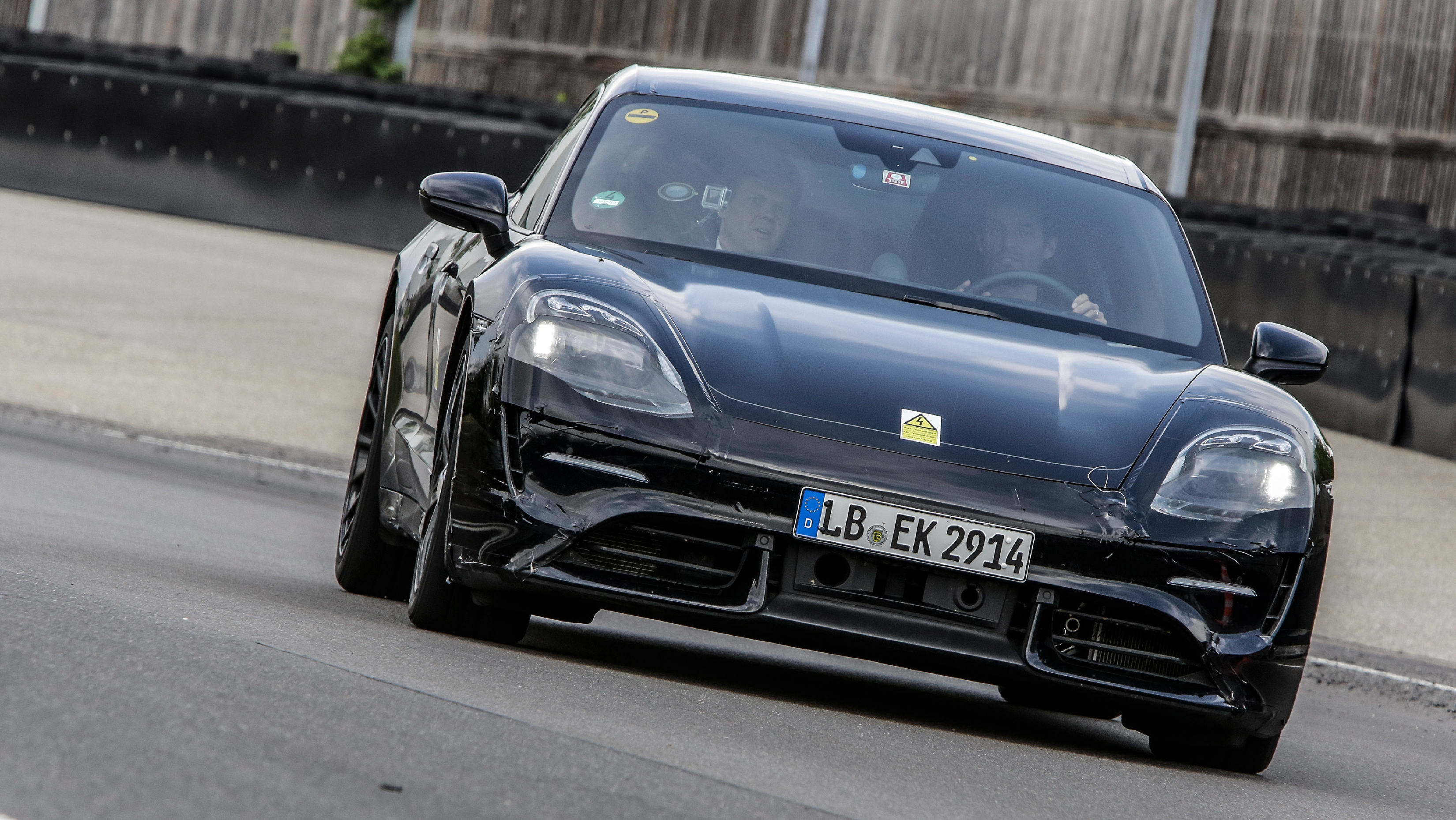 A black Porsche sedan on a racetrack.