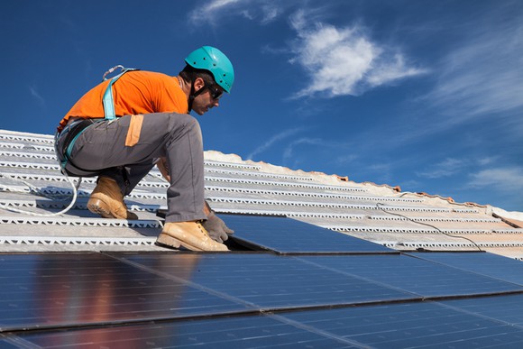 A man installing rooftop solar panels.