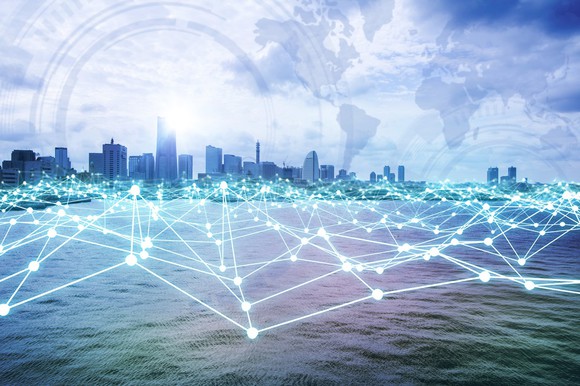 A view of a city skyline from the water, with a digital network overlaid on top.