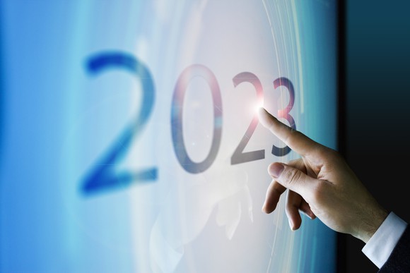 Finger touching a screen displaying the number 2023.