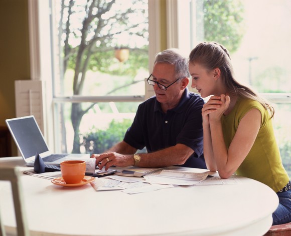 Man and girl at a laptop with paperwork spread out in front of them