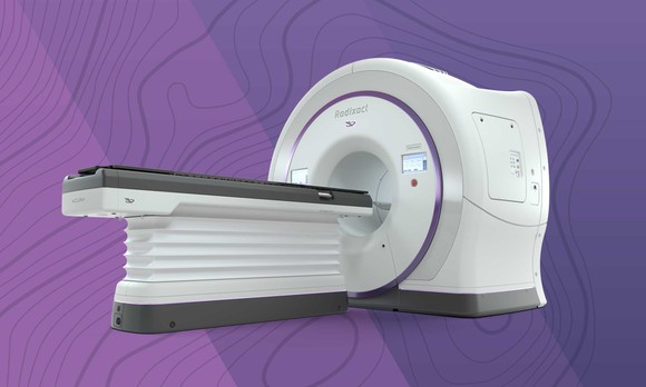 White machine with flat surface for a person to lie and a hole for scans of a patient's head.