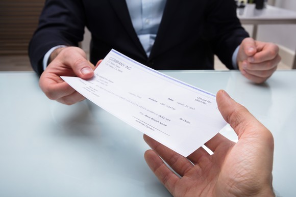Man in suit handing over a paycheck