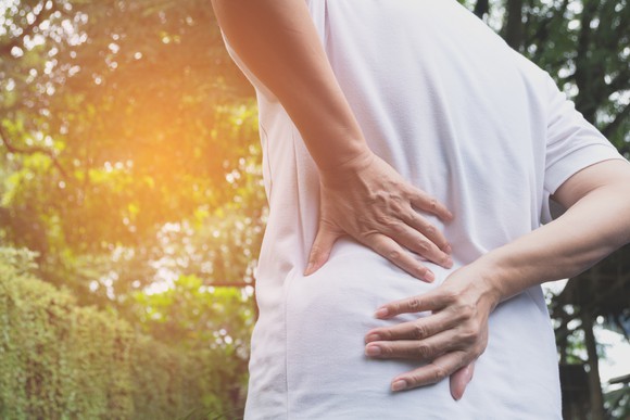 A person grabbing their back, seen from behind
