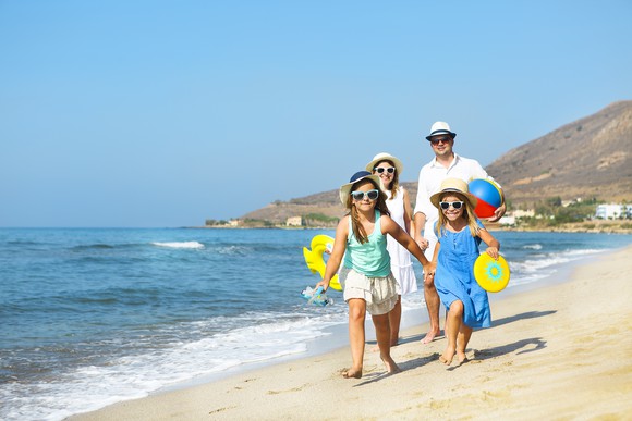 Man, woman, and two young girls walking on the beach