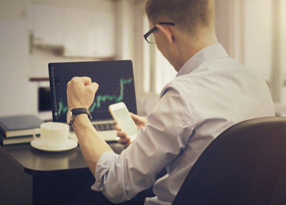 Man sitting at desk looking at smartphone.
